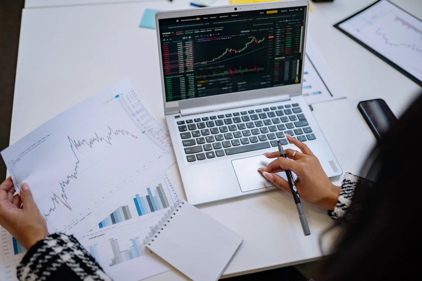 A detailed look at business analysis with a laptop displaying graphs and financial charts on a table.