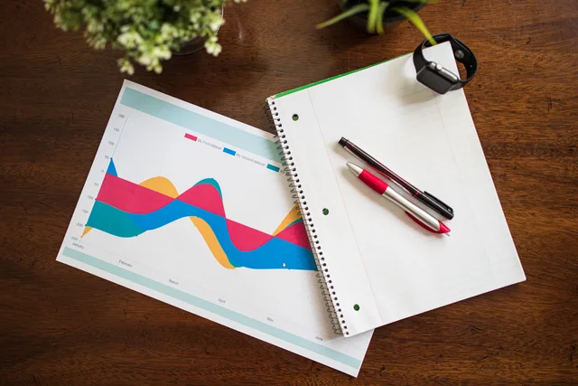 Top view of a workspace with graph, notebook, pens, and smart watch. How UK agencies can assess SEO tools